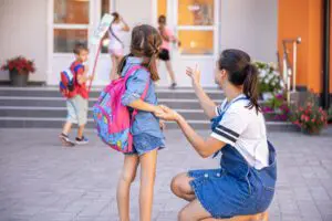A mother accompanies student to school, happy little girl with a caring mom, back to school.