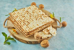 pesach-celebration-concept-jewish-passover-holiday-matzah-on-wooden-stand-with-nuts-1024x698