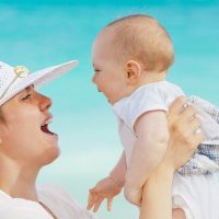 אמא-מחזיקה-תינוק-בידיים-ומניפה-אותו-על-רקע-ים_1200X600